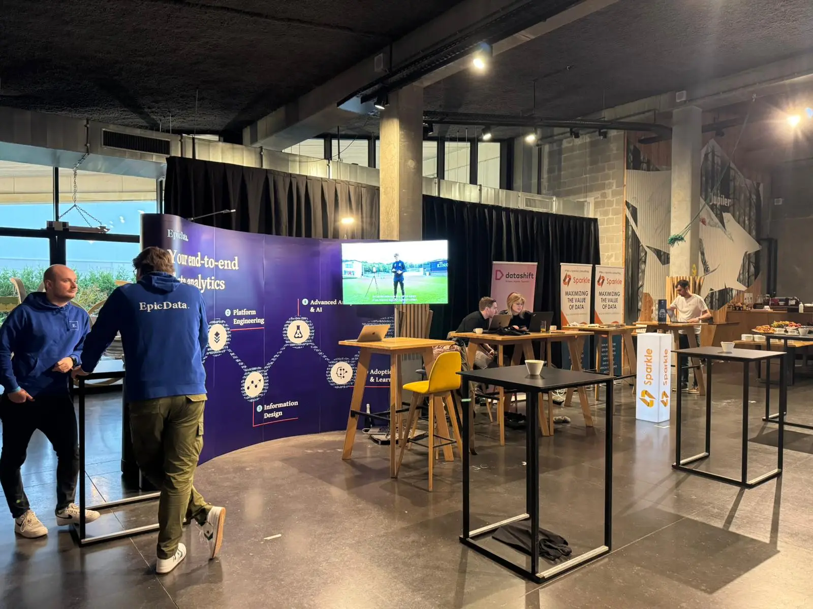 Partners talking with attendees at a curved stand