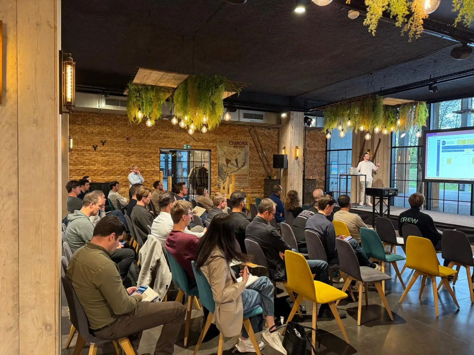 Attendees filling the main session room under the hanging greenery